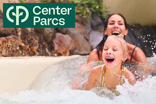 Ein Kind rutscht mit seiner Mutter eine Wasserrutsche hinunter