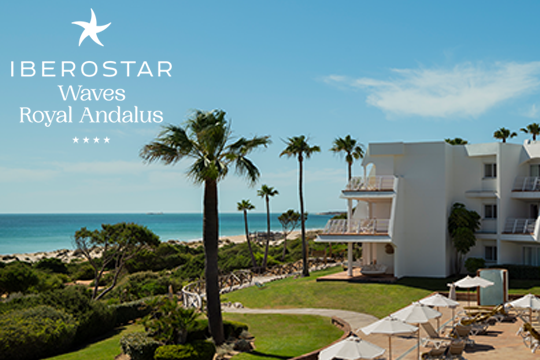 Hotelanlage in wei&szlig; mit Palmen und links das Meer